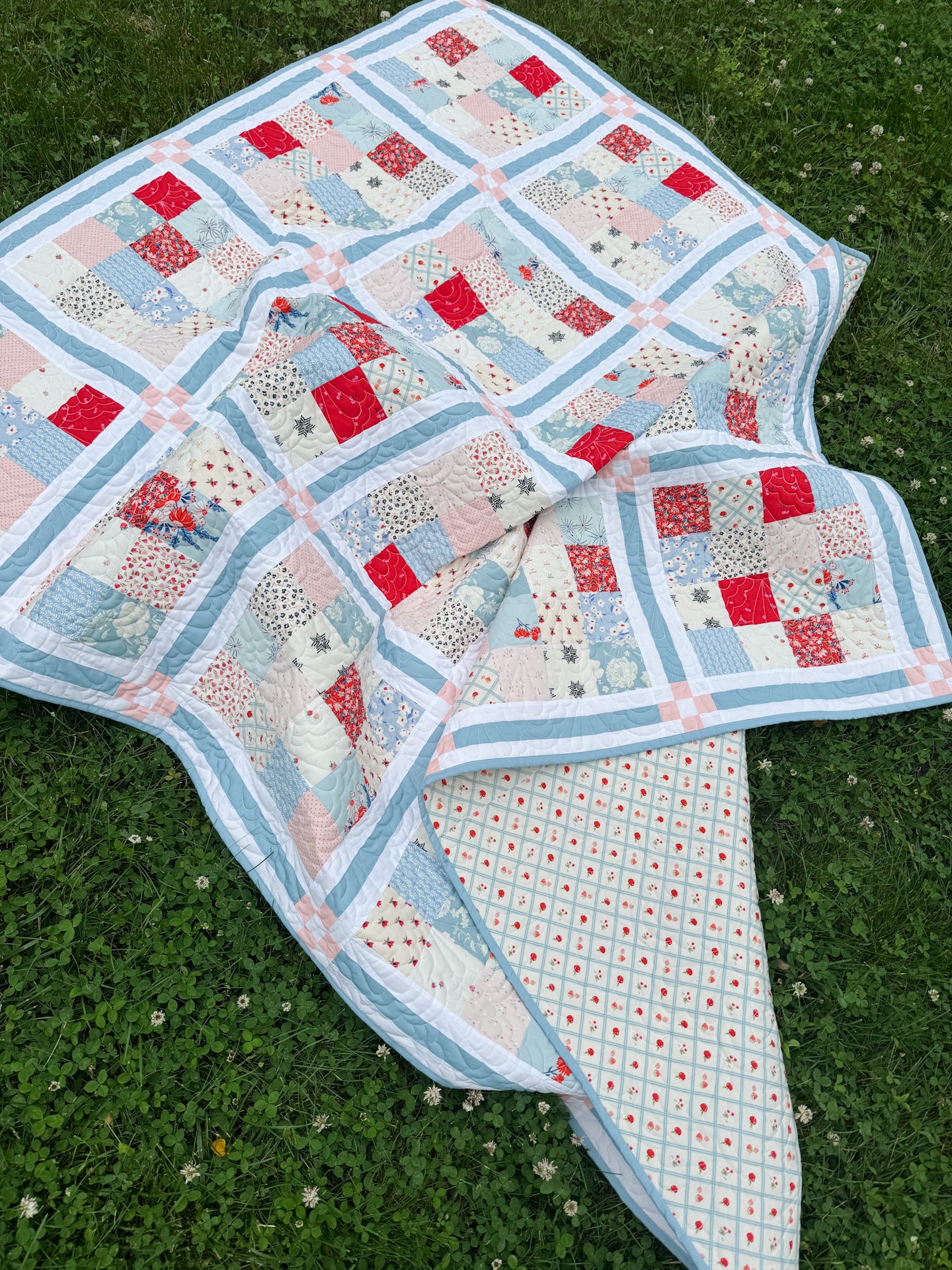 Quilt with a patchwork design on a grassy background