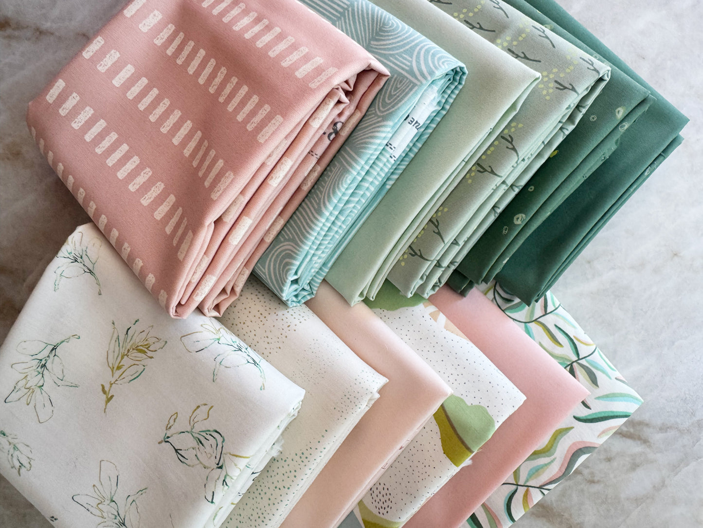 Stack of folded fabric swatches in various patterns and colors on a neutral background