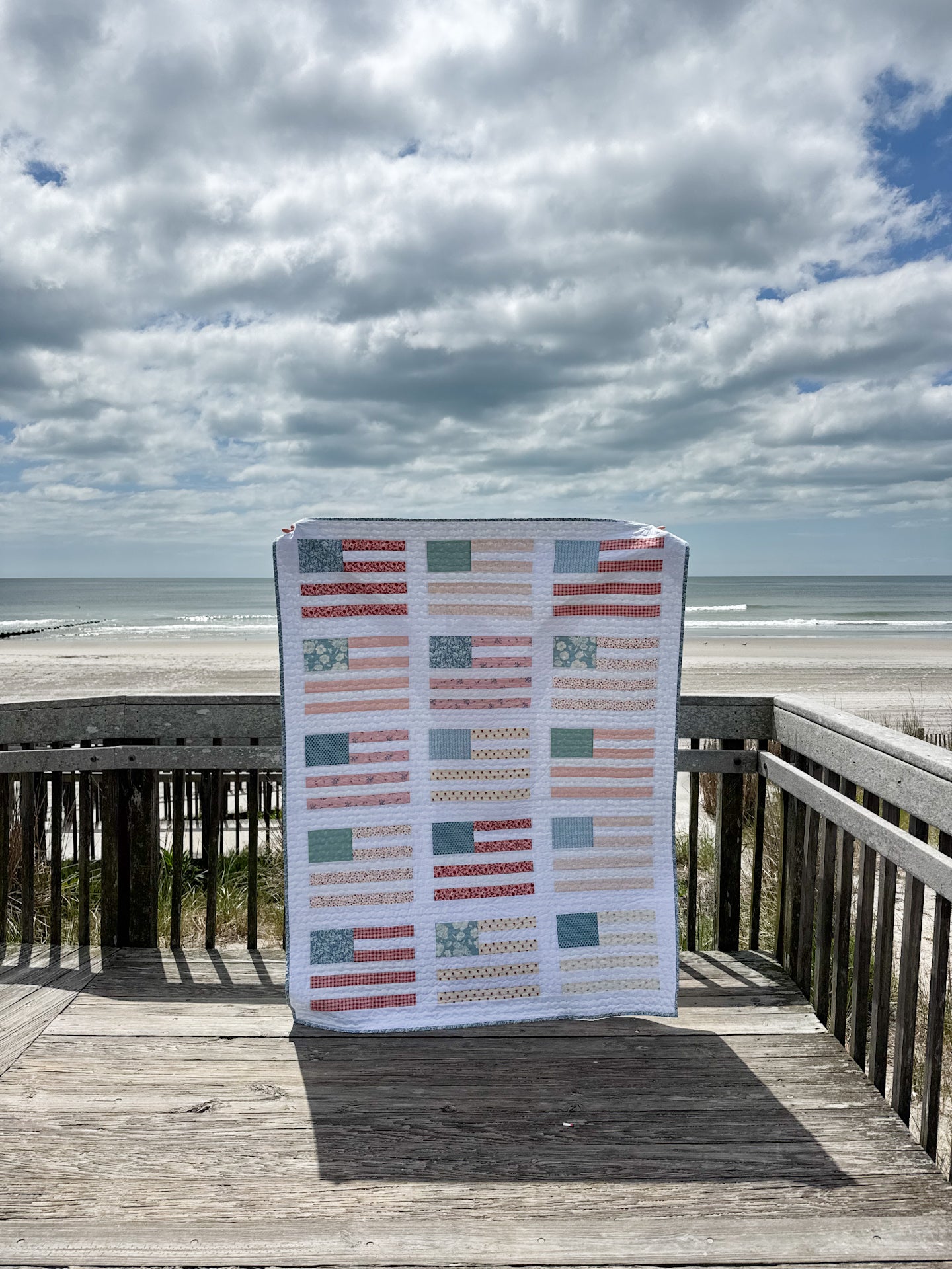 Quilt with geometric pattern on a wooden deck by the ocean